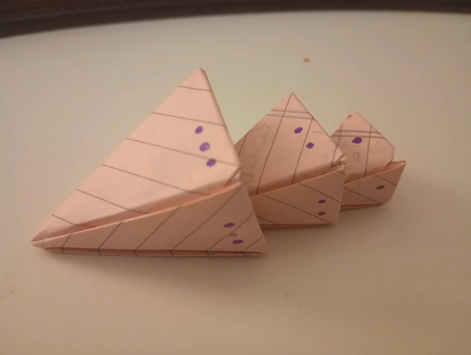 three paper pyramids of different sizes, laying on the table as if a stack were just tipped over.